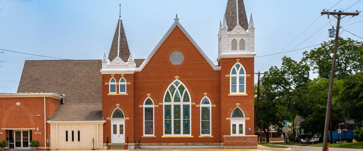 A large brick church with two steeples and arched windows.