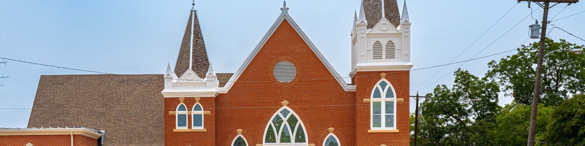 A large brick church with two steeples and arched windows.