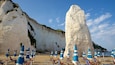 Een strand met witte kliffen en blauw-gestreepte strandparasols.