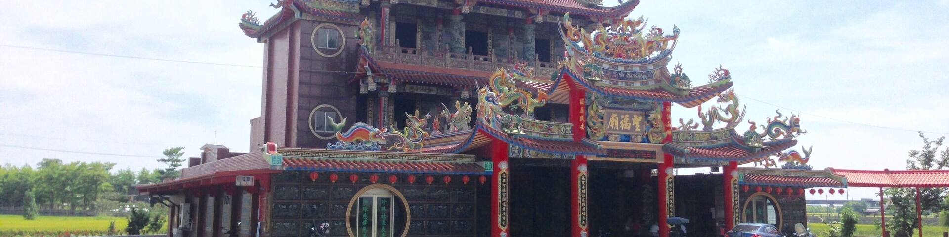 A traditional multi-tiered temple with ornate decorations and a red roof.