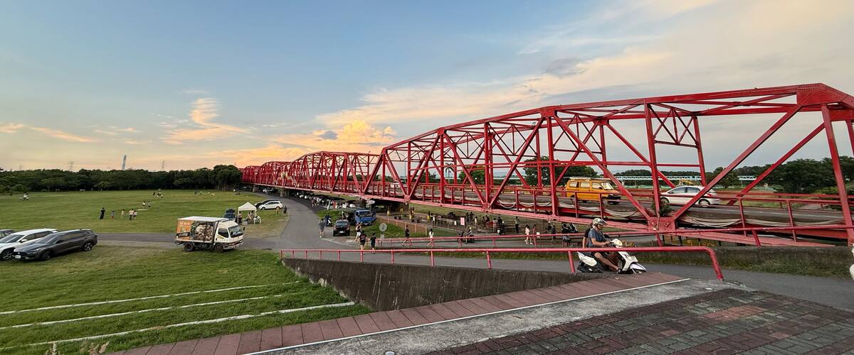A red bridge over a road with cars and a truck.