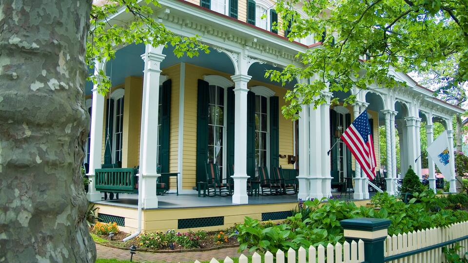 A historic building with a porch, columns, and an American flag.