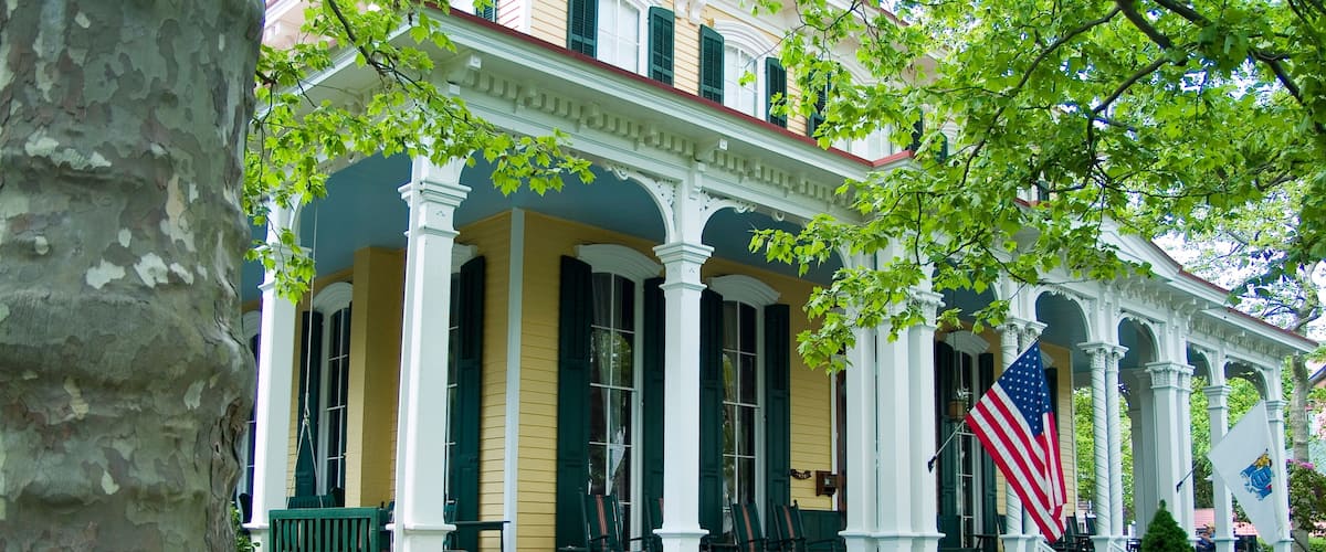 A historic building with a porch, columns, and an American flag.