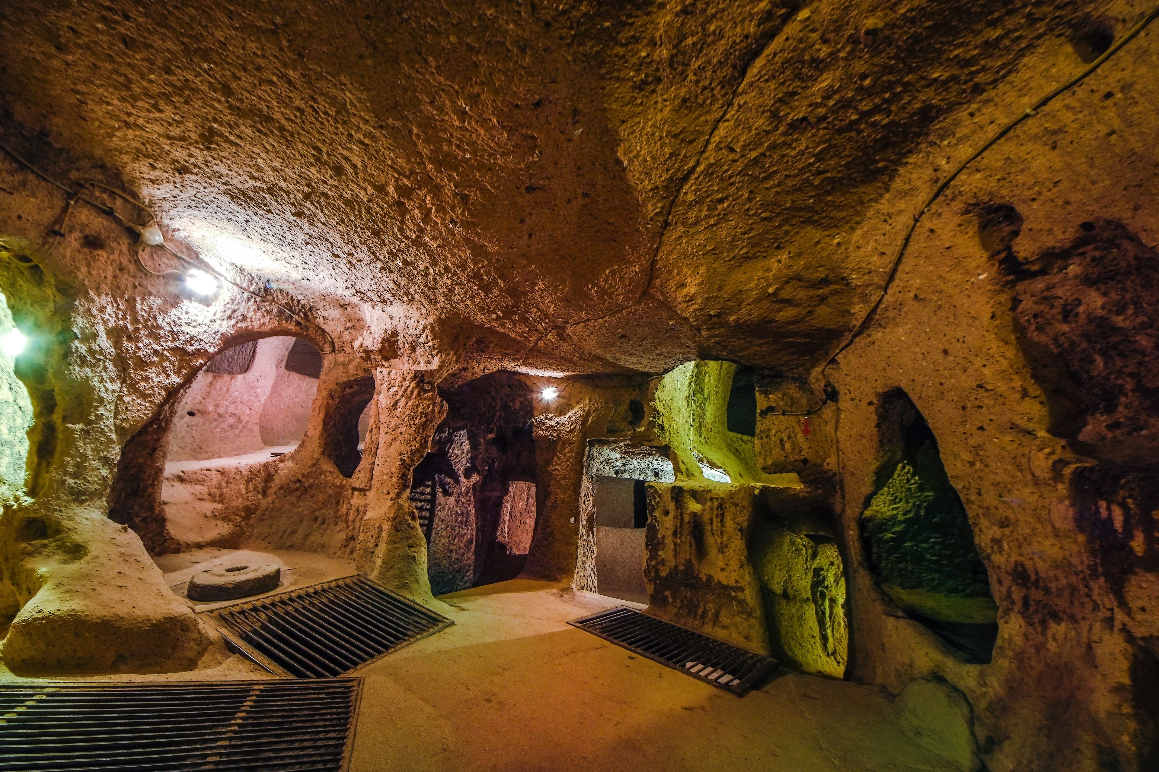 A cave interior with stalactites, a water drainage system, and a natural archway.