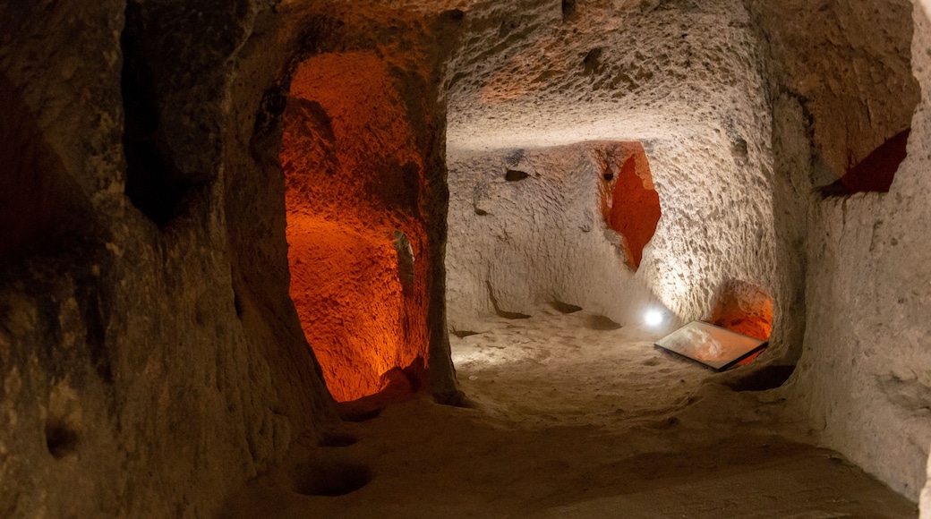 An underground passage with rough stone walls and a bright orange glow from a light source.
