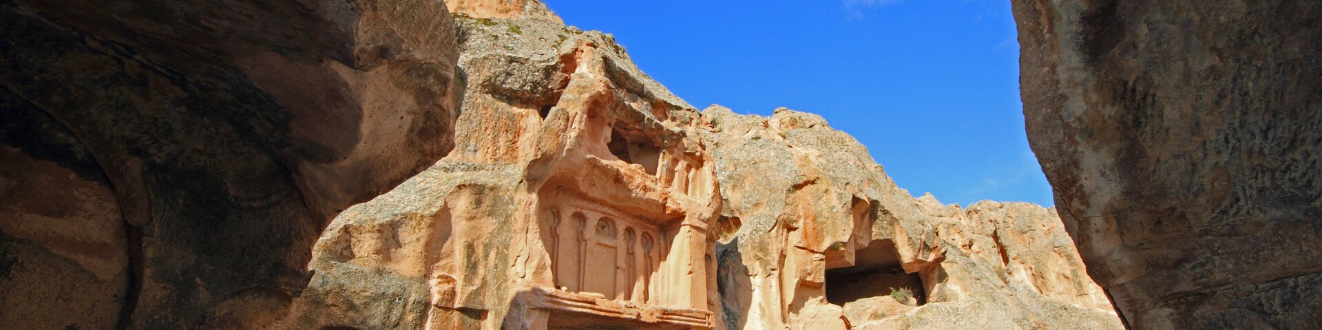 Una estructura excavada en la roca con un arco, tallada en un acantilado.