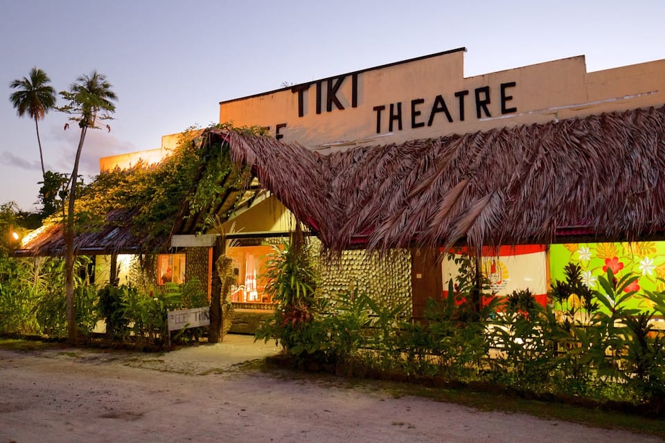 A building with a sign reading "TIKI THEATRE" and a thatched roof.
