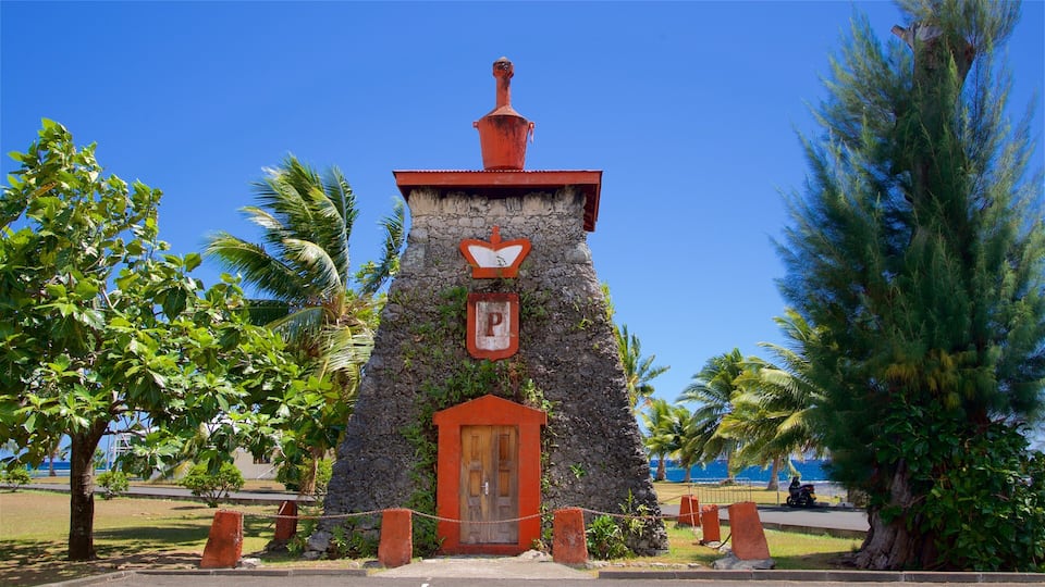 A lighthouse with a red roof and a wooden door, surrounded by palm trees and a clear blue sky.
