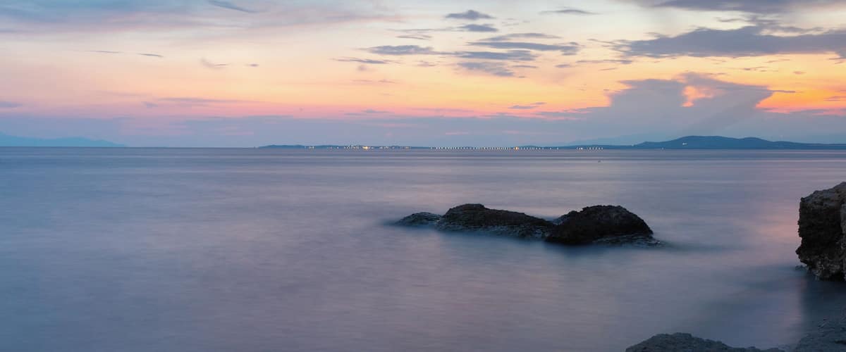 A coastal landscape with rocky formations and calm waters.