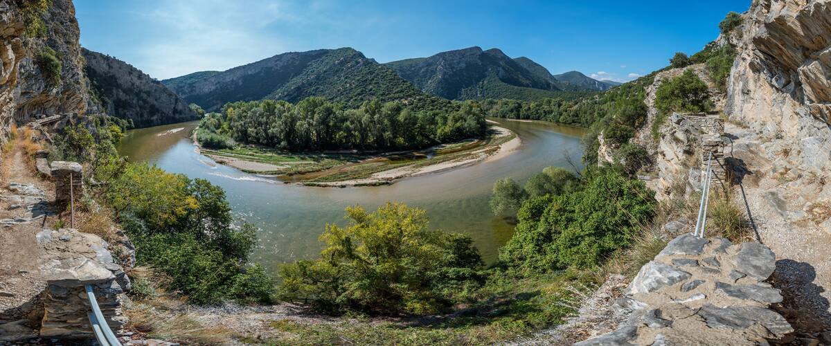 A river winding through a valley with rocky cliffs on either side and a forested area in the center.
