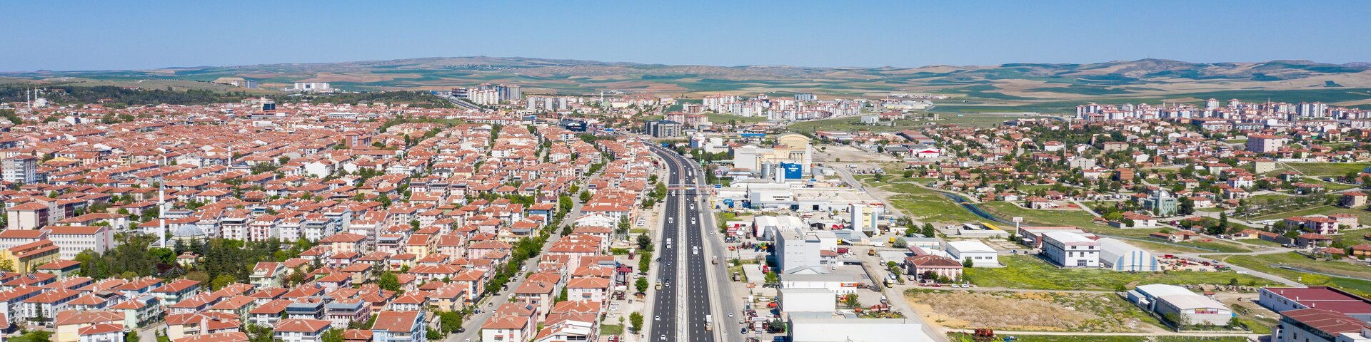 A cityscape with a central road, residential areas, and industrial buildings.