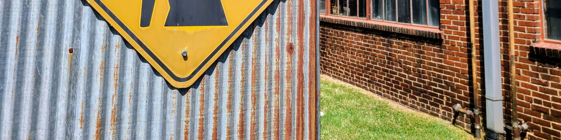 Industrial Caution Sign on Corrugated Metal Eye-Level Perspective