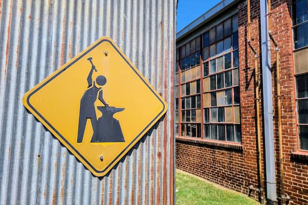 Industrial Caution Sign on Corrugated Metal Eye-Level Perspective
