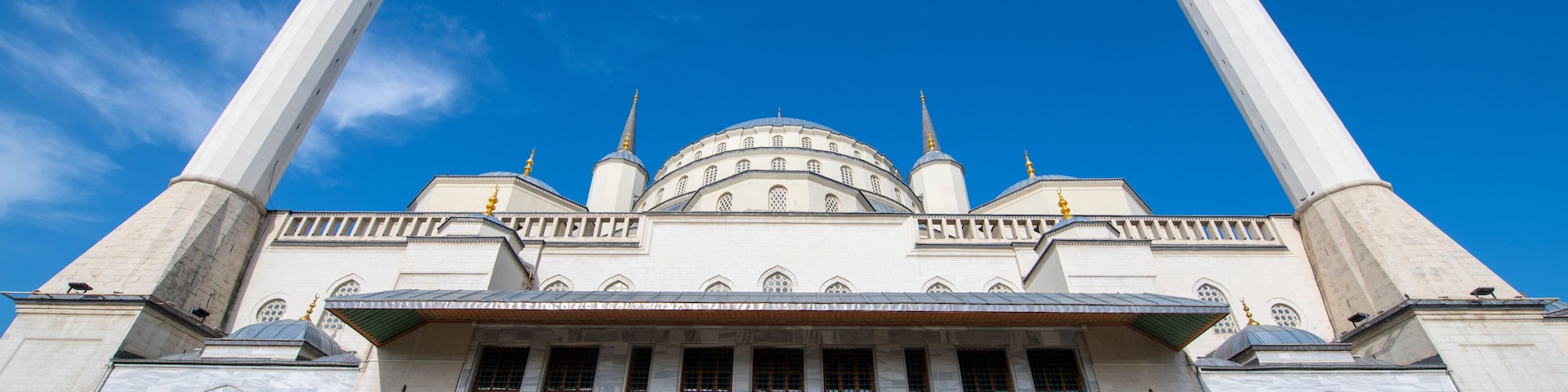 Une grande mosquée dotée de deux hauts minarets, d’un dôme central et de nombreuses fenêtres en arc.