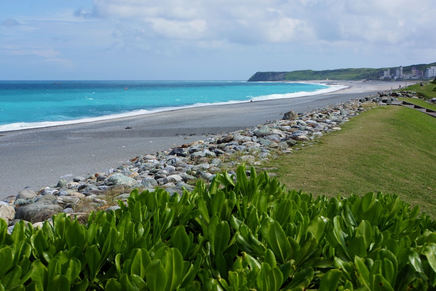 Un paisaje costero con una costa rocosa, una playa arenosa y una colina cubierta de hierba.