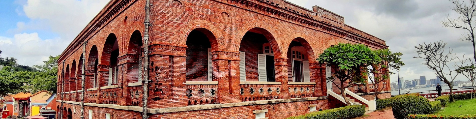 Un edificio de ladrillo rojo con ventanas arqueadas y una escalera que lo conduce.