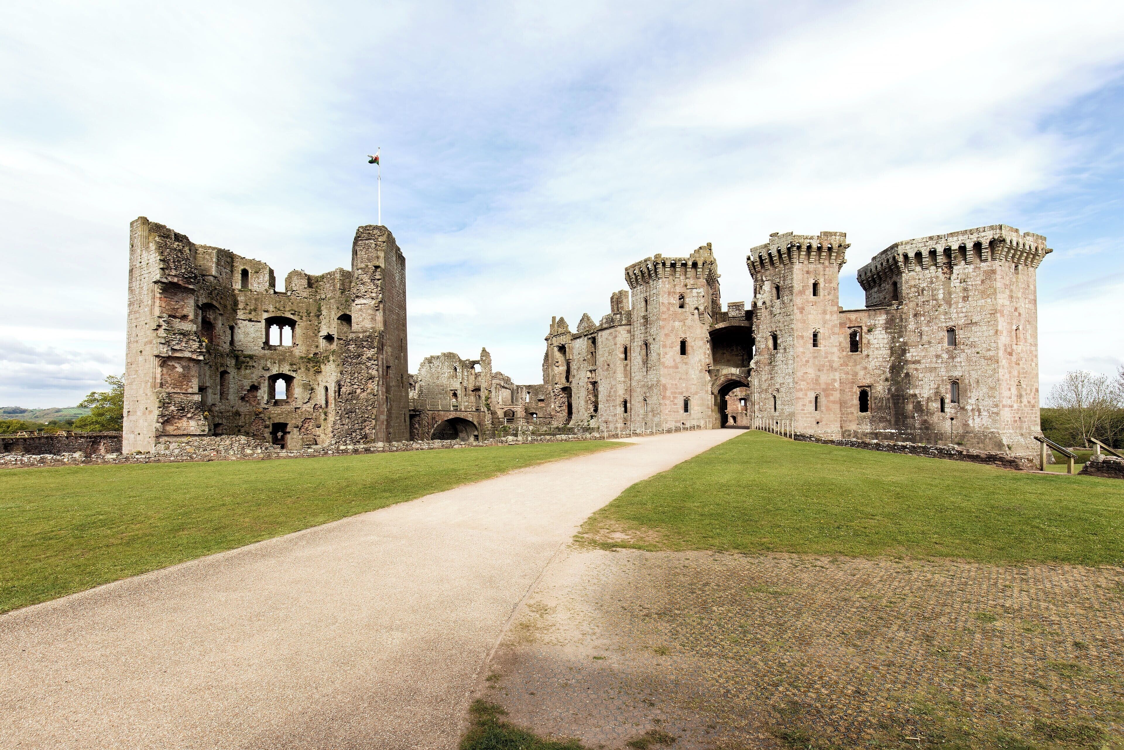 A historic castle with a central tower, a large courtyard, and a flag on top.