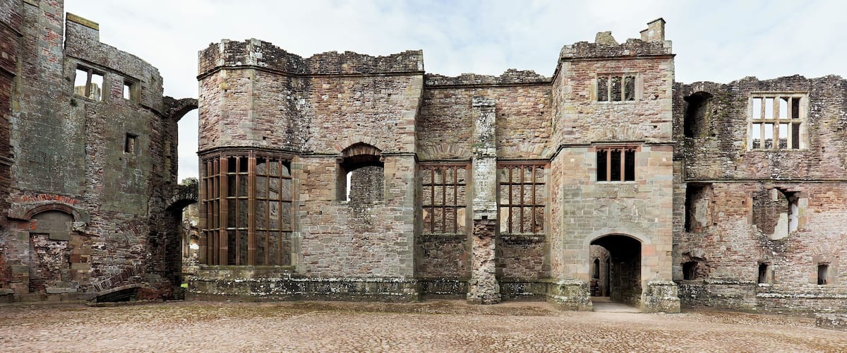 An old stone building with arched windows and a cobblestone courtyard.