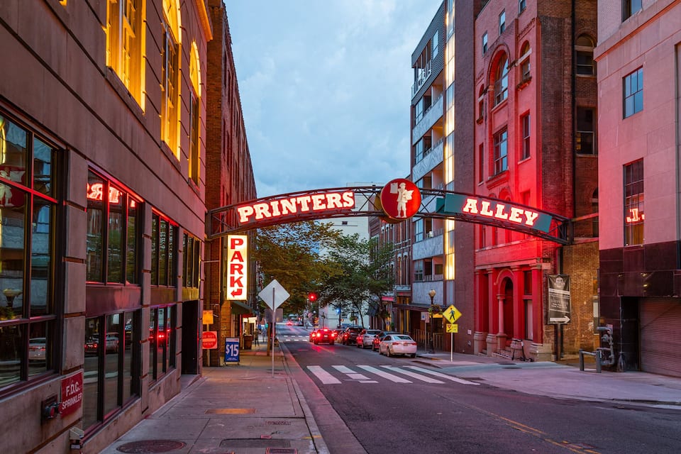A street with buildings, a sign reading "Printers Alley", and a crosswalk.