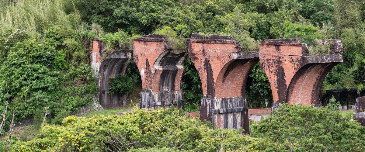 A series of brick arches amidst lush greenery.