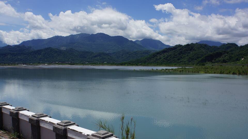 A calm lake with mountains in the background and a clear sky.