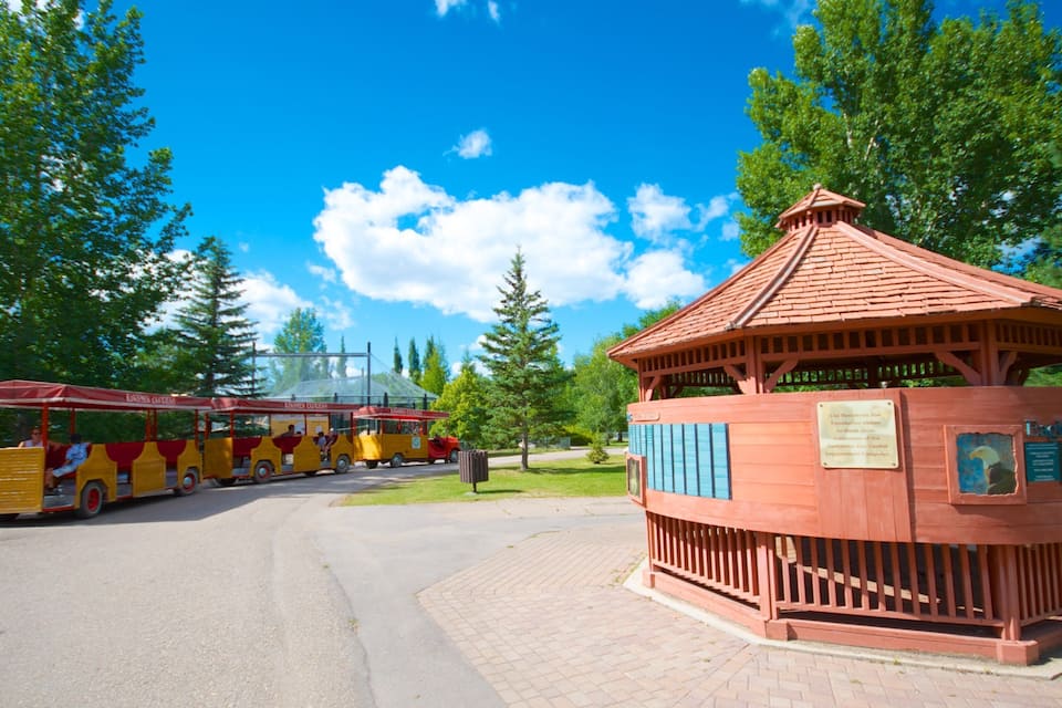 A zoo entrance with a red-roofed pavilion and a yellow bus.