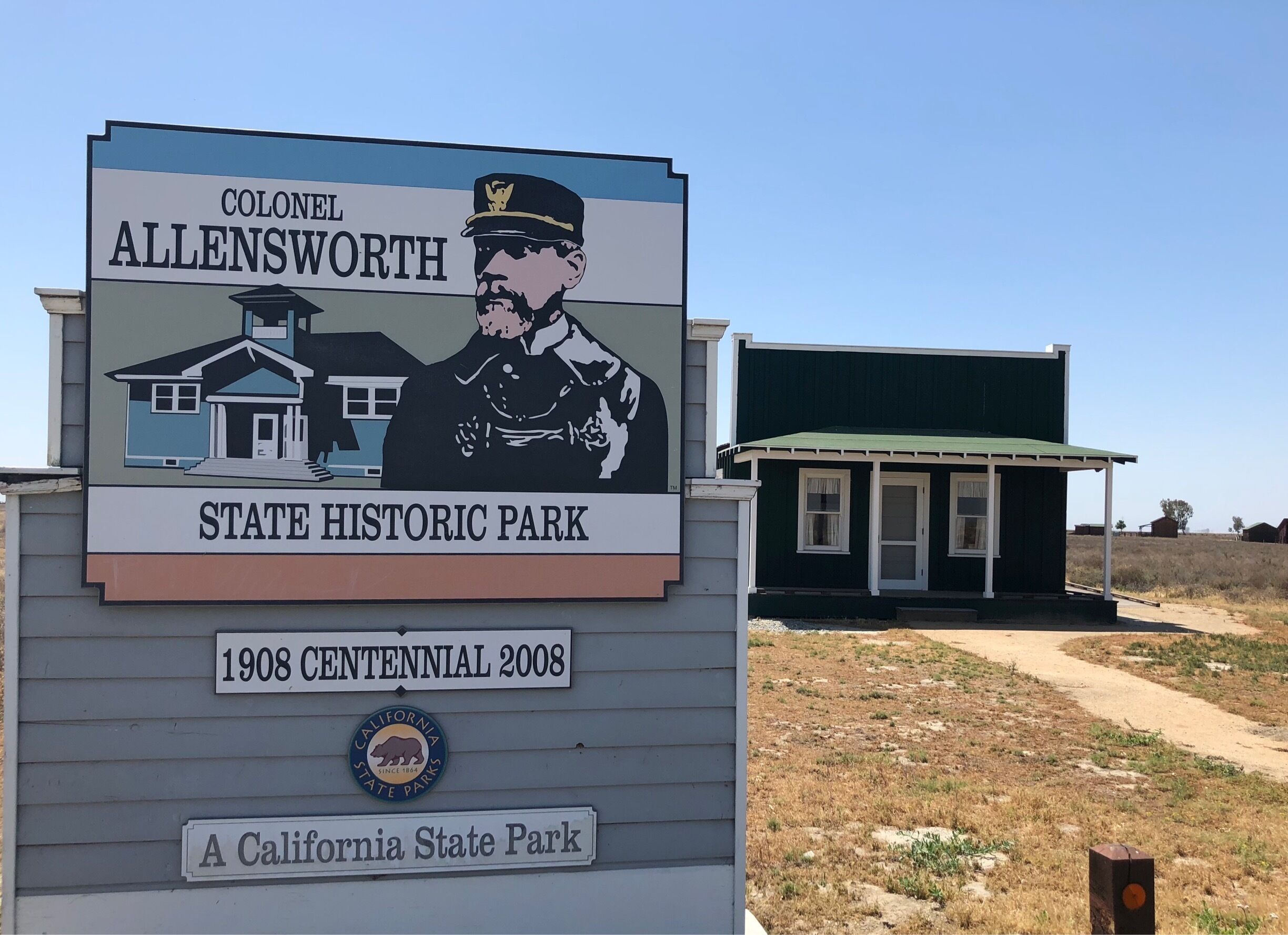 A sign for the Colonel Allensworth State Historic Park, featuring a building and a portrait of a man in uniform.