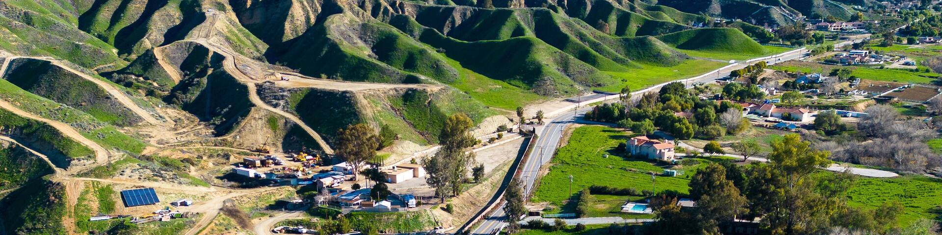 A winding road through a hilly landscape with a mountain range in the background.