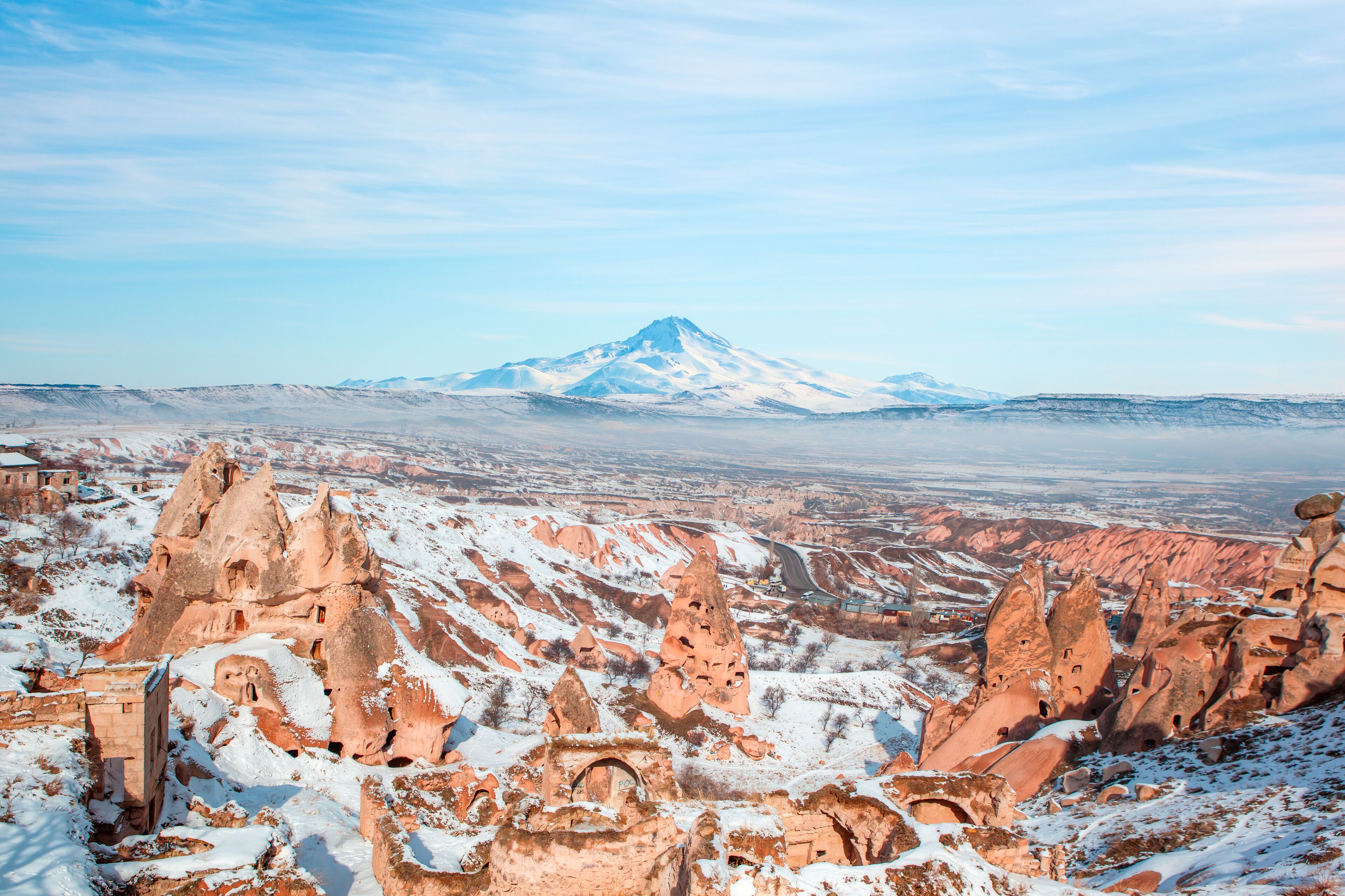 A snow-covered mountain with unique rock formations in the foreground.