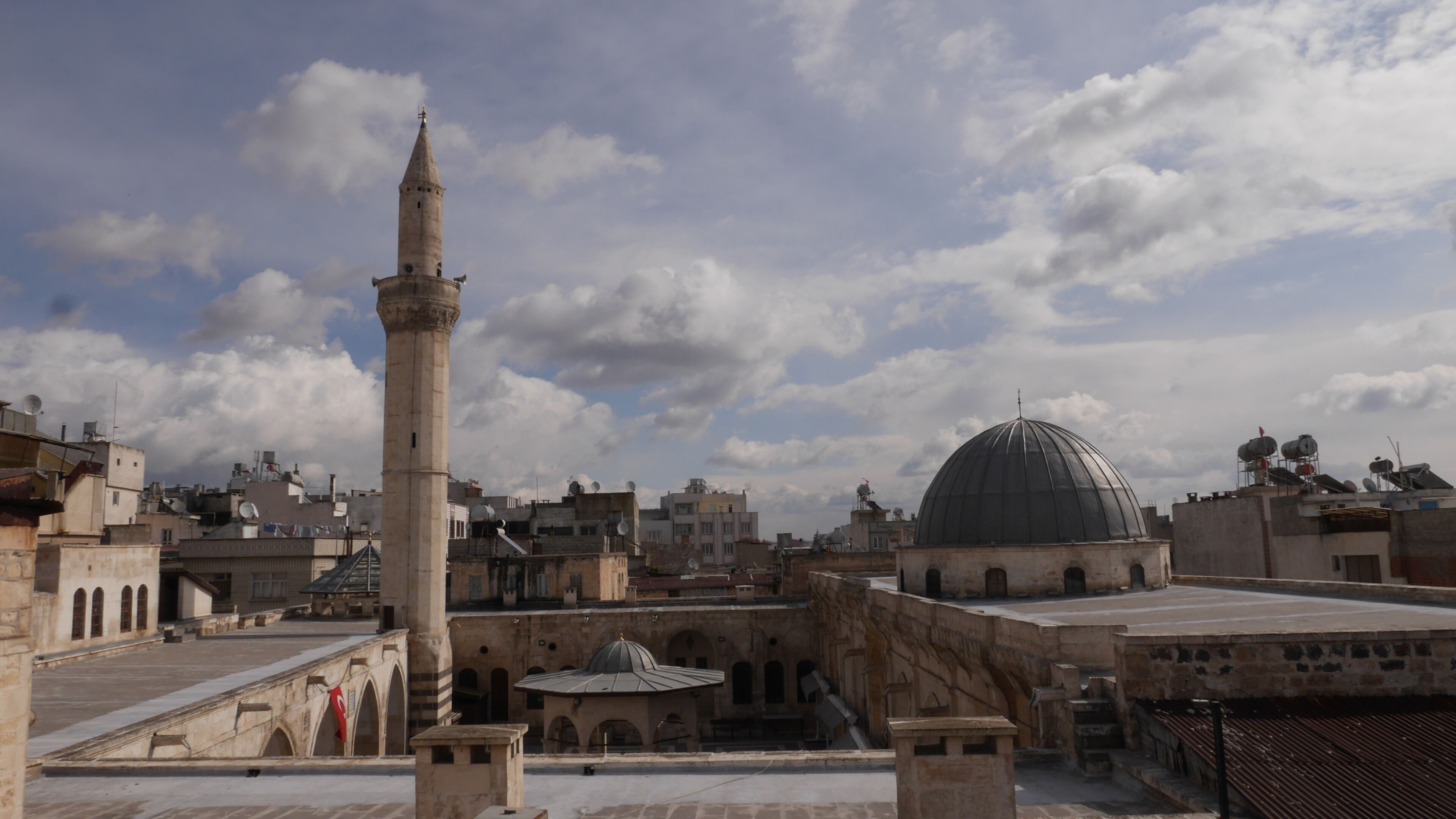 A mosque with a tall minaret and a large dome, surrounded by historic buildings.
