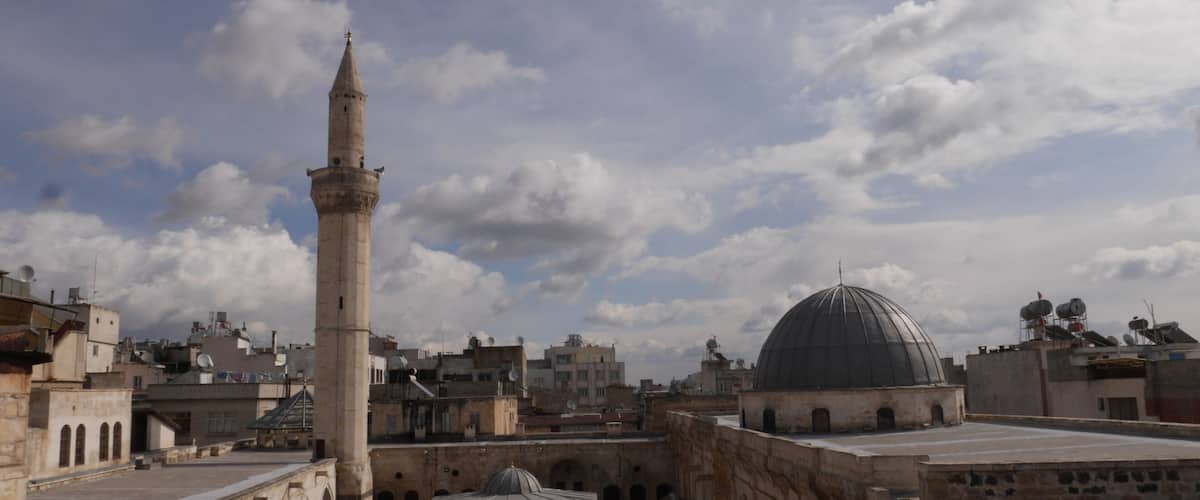 A mosque with a tall minaret and a large dome, surrounded by historic buildings.