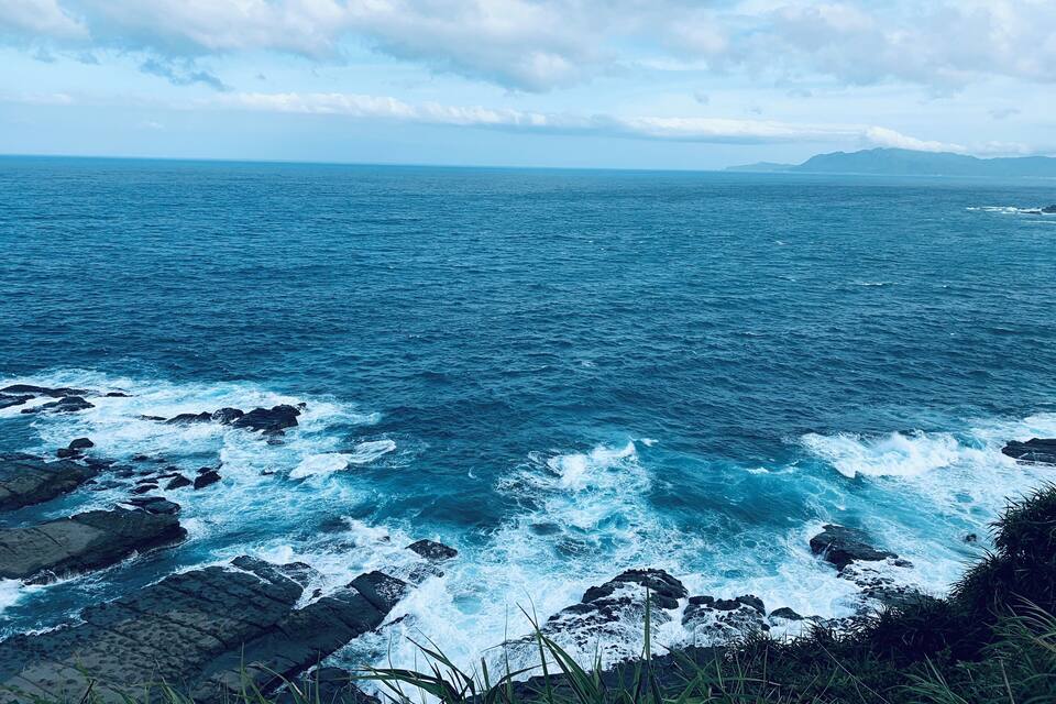 Un paisaje costero con costas rocosas y olas rompiendo contra las rocas.