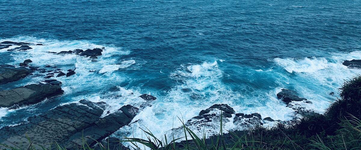 A coastal landscape with rocky shores and waves crashing against the rocks.
