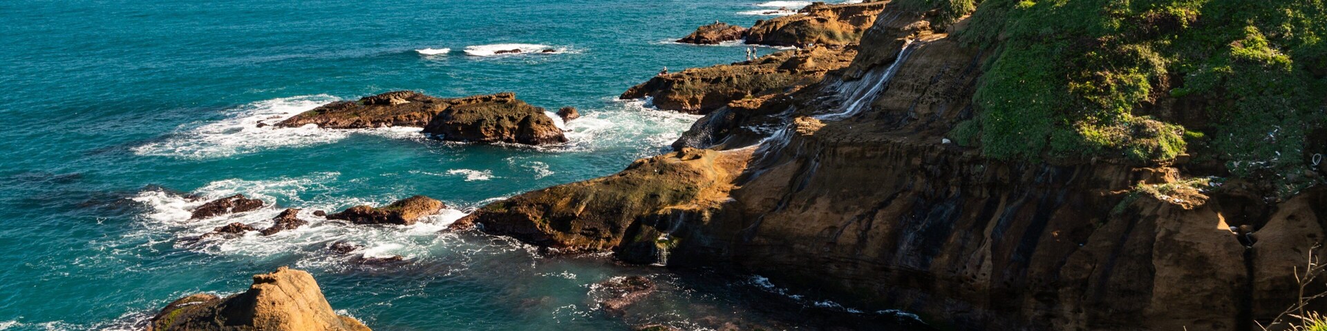 Un paisaje costero con acantilados rocosos, vegetación verde y el océano.
