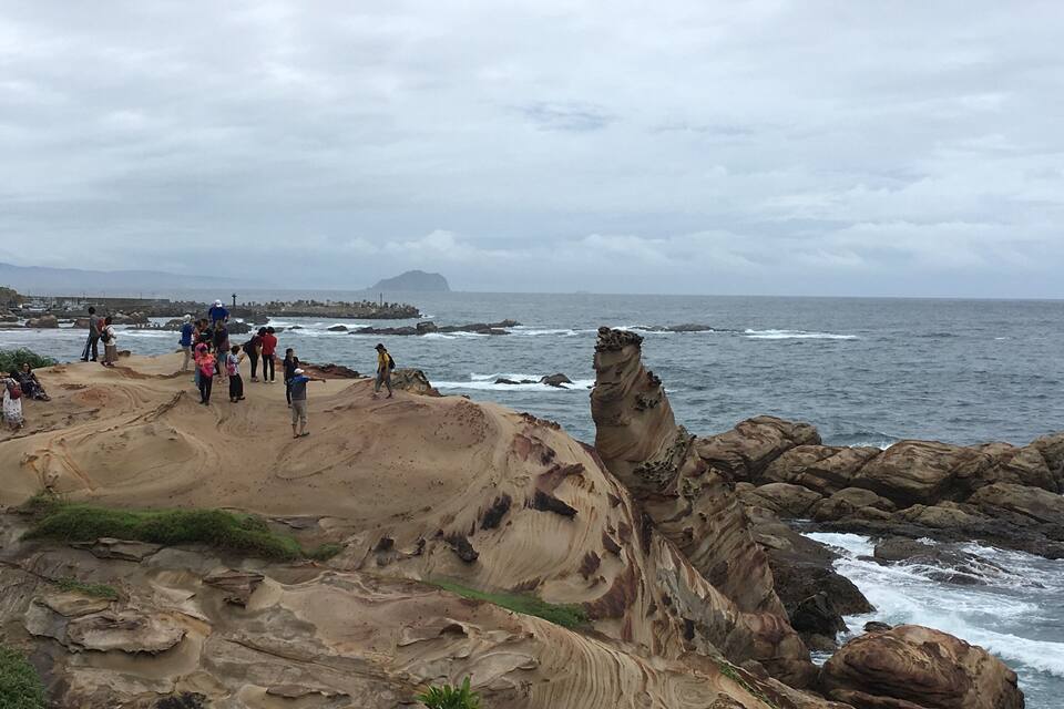 Un paisaje costero rocoso con gente mirando al mar.