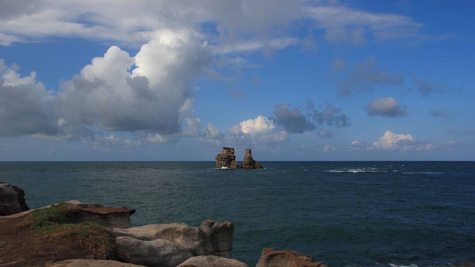 Una costa rocosa con una formación rocosa destacada en el mar.