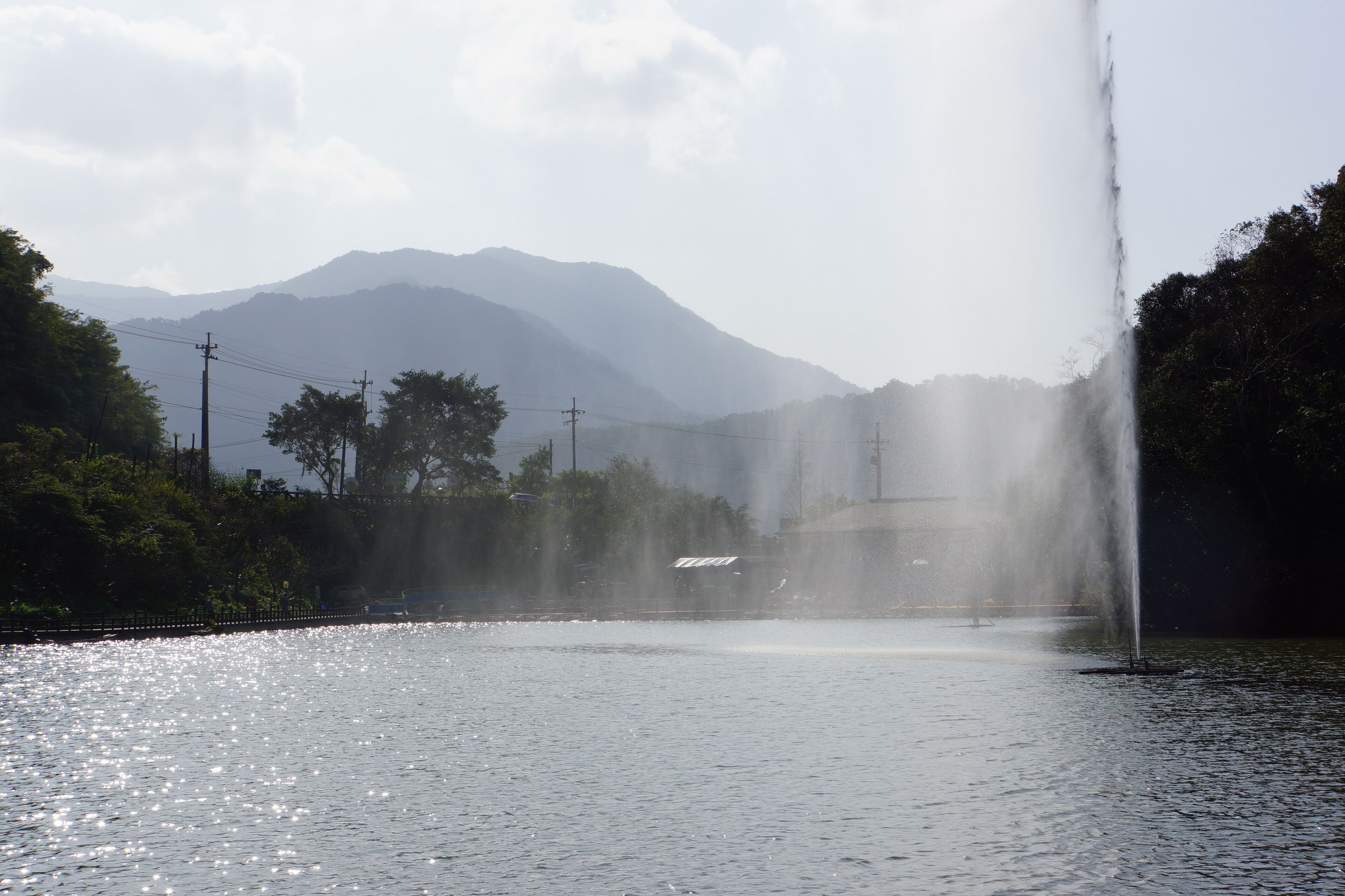 A fountain in a park with mountains in the background.