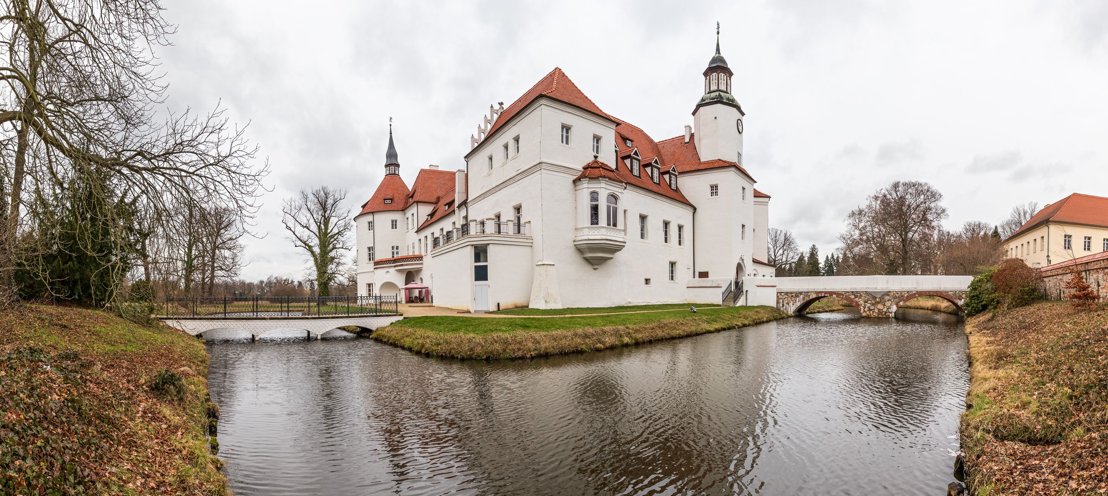 A large white castle with red roofs and a moat.