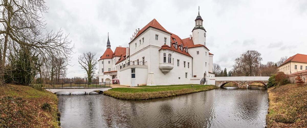 A large white castle with red roofs and a moat.