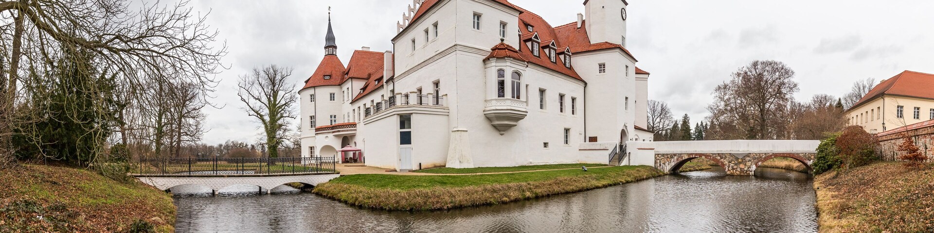A large white castle with red roofs and a moat.