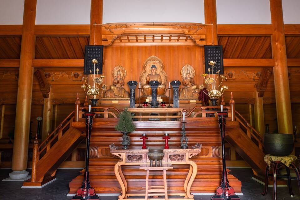 Um santuário de madeira com estátuas, queimadores de incenso e instrumentos rituais.