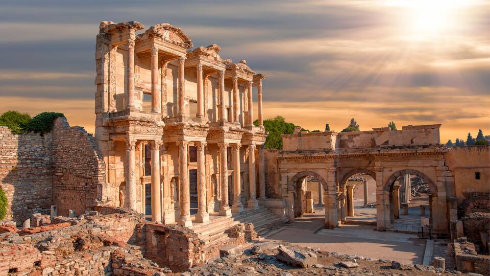 Ancient ruins with columns and arches under a cloudy sky.