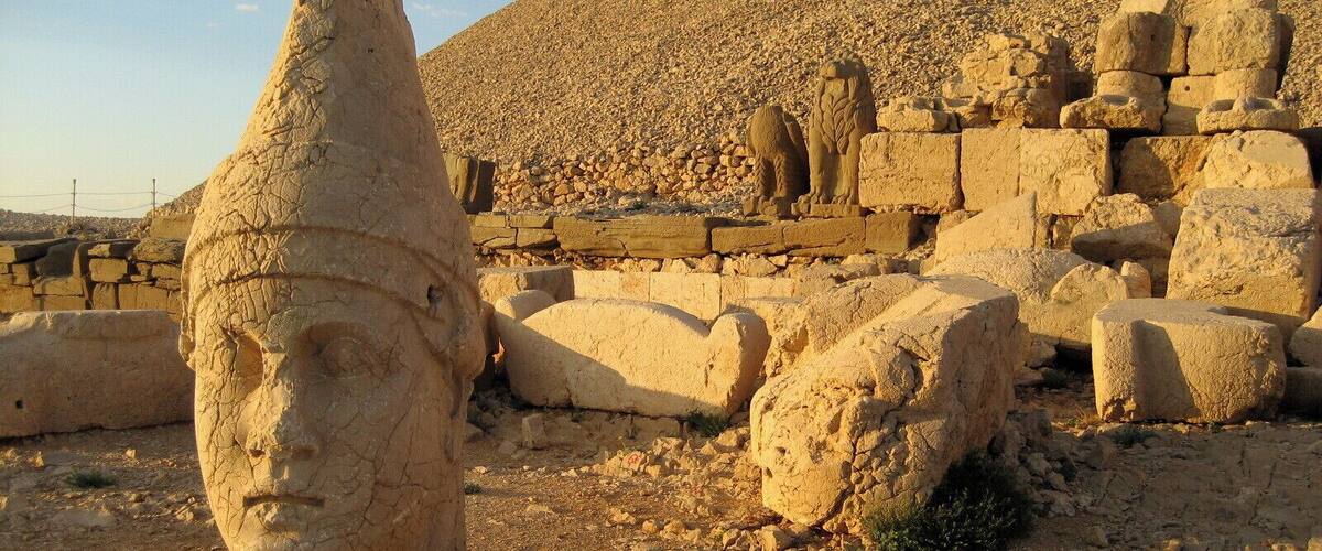 Ancient Egyptian ruins with a large pyramid in the background and a stone head in the foreground.