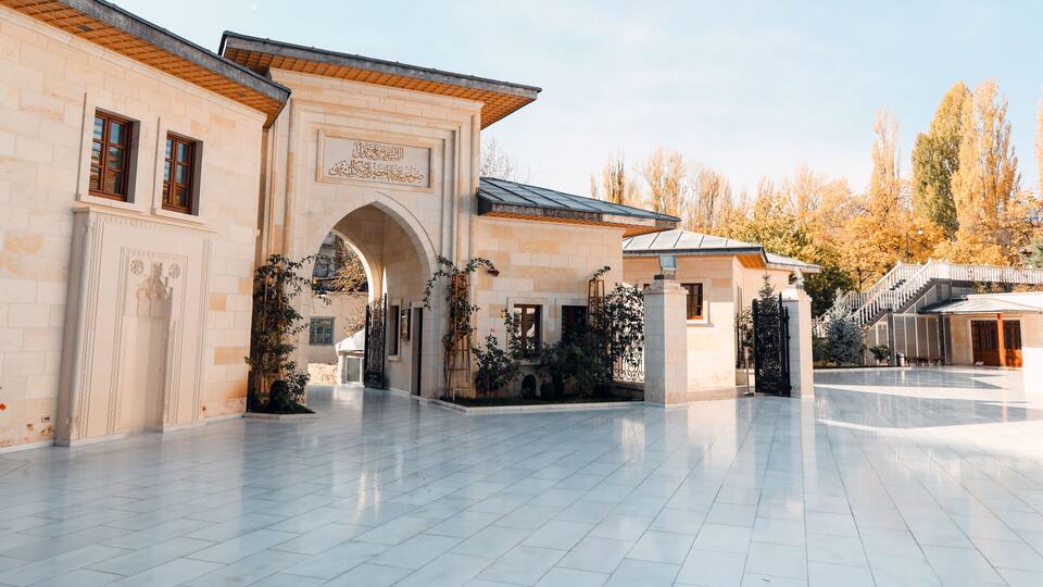 A courtyard with a large archway, tiled floor, and surrounding buildings.