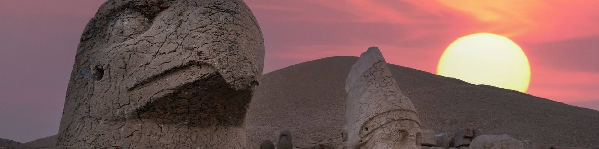 View of mount Nemrut and monumental sculptures of commagene kings and gods with colorful clouds and sun at sky