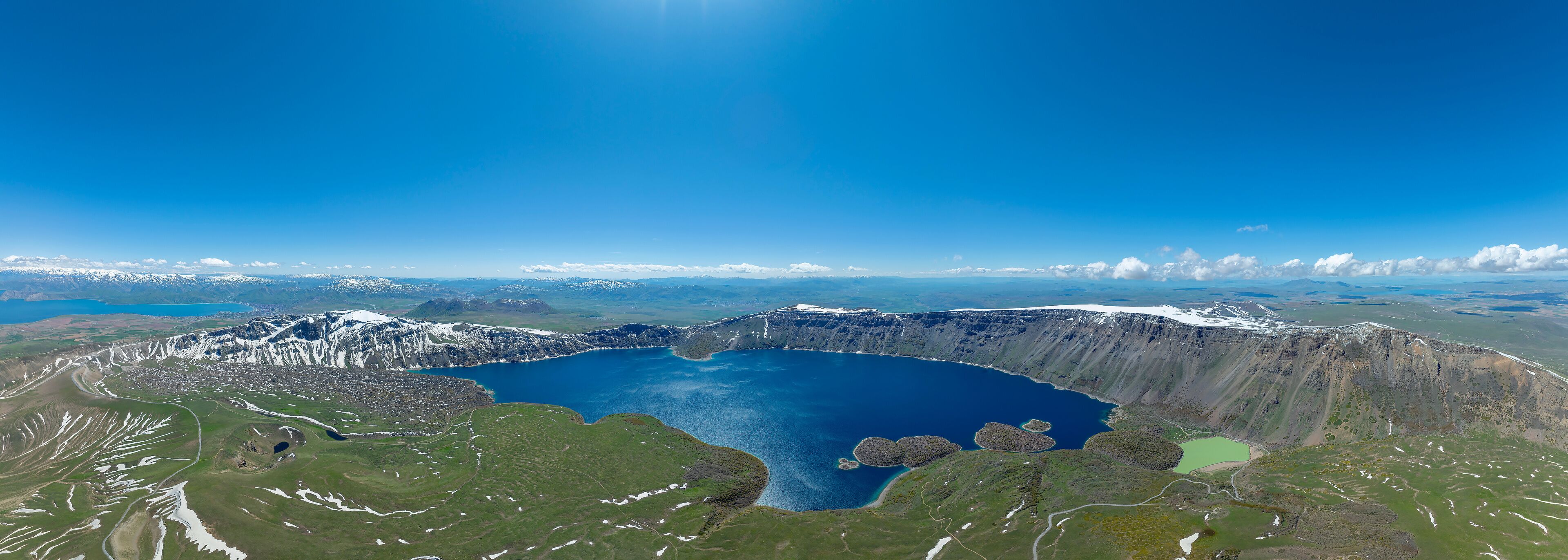 A large crater lake surrounded by mountains and snow-covered peaks.