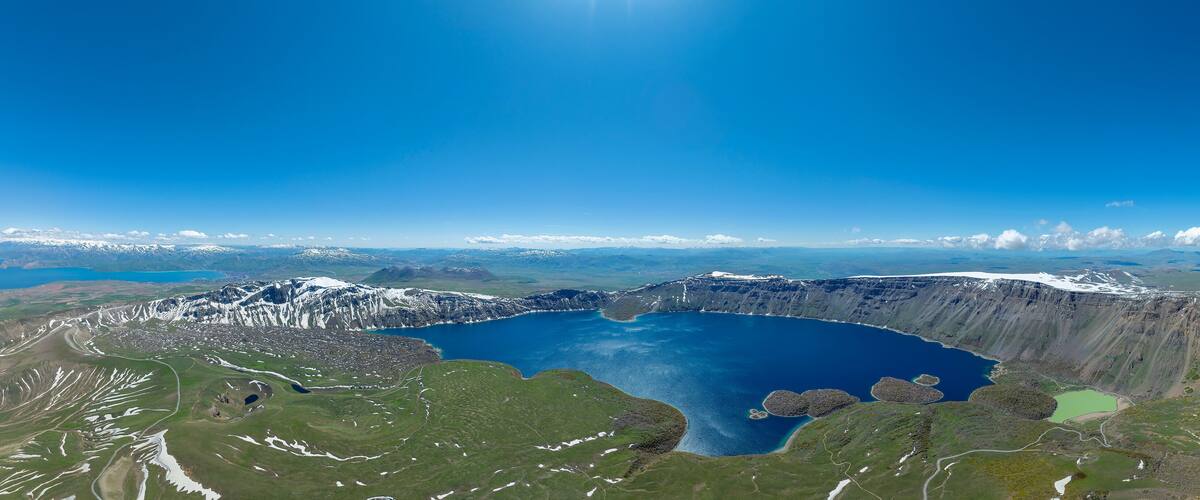 A large crater lake surrounded by mountains and snow-covered peaks.