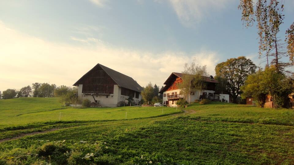 A rural landscape with a barn, a house, and a field.