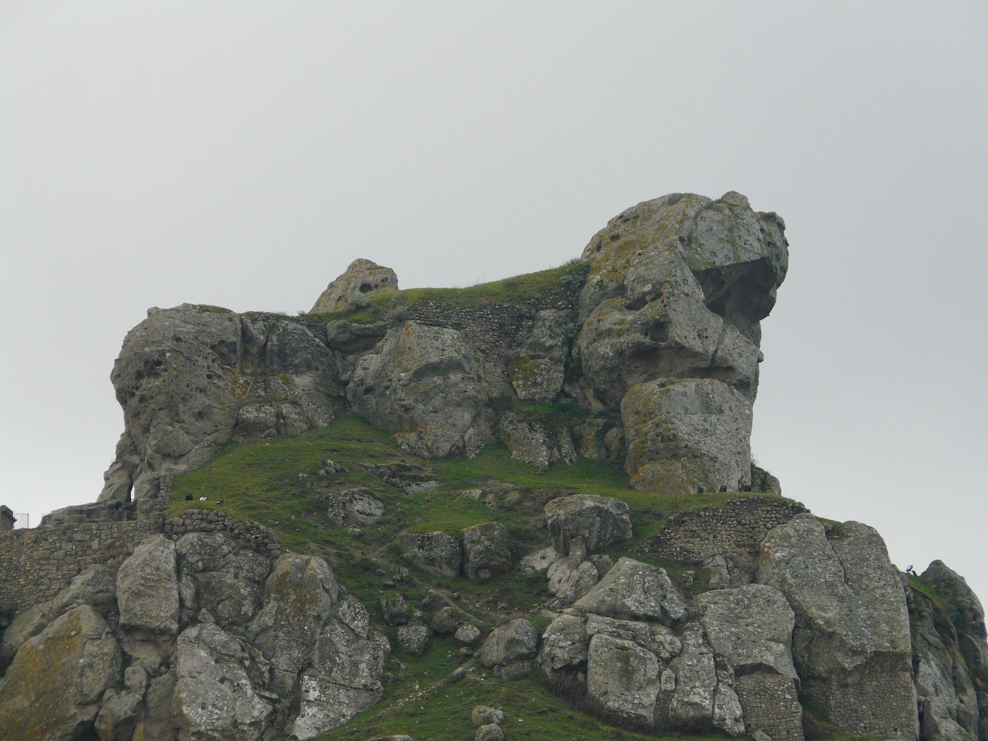 A rugged, rocky mountain peak with patches of grass and moss.