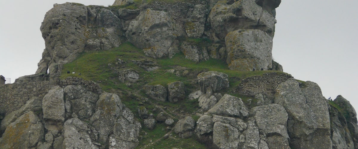 A rugged, rocky mountain peak with patches of grass and moss.